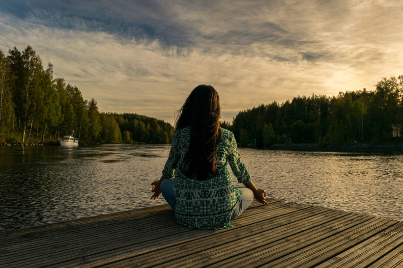 dziewczyna medytuje nad jeziorem, zachód słońca